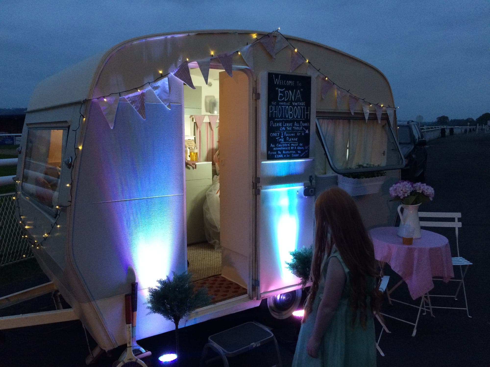 A guest stepping into Edna in the evening, the interior lit blue and pink